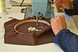 Artisan embroidering fabric with a machine, showcasing detailed craftsmanship in Fès, Morocco.